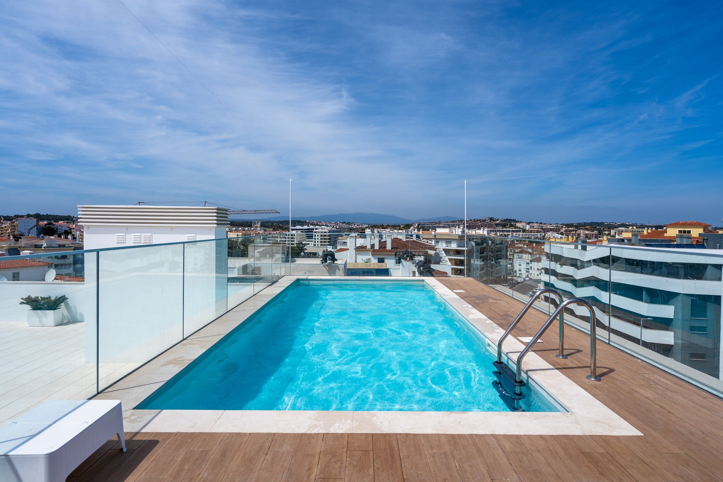 Rooftop pool on a modern building, with a glass balustrade and views over the town