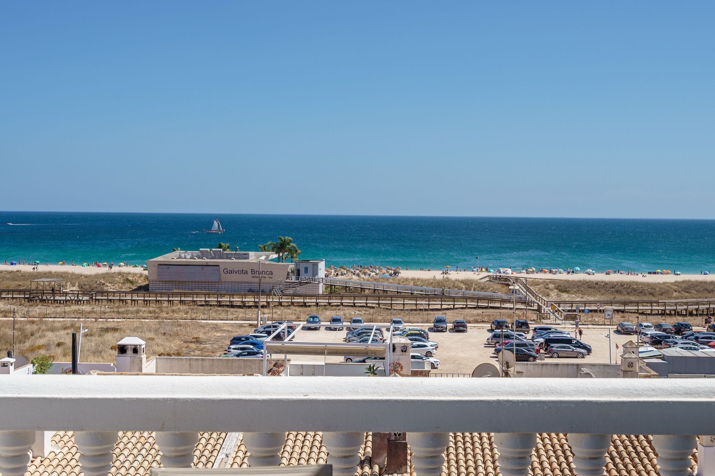 View from a balcony over Meia Praia beach and the sea, with the boardwalk and the dunes