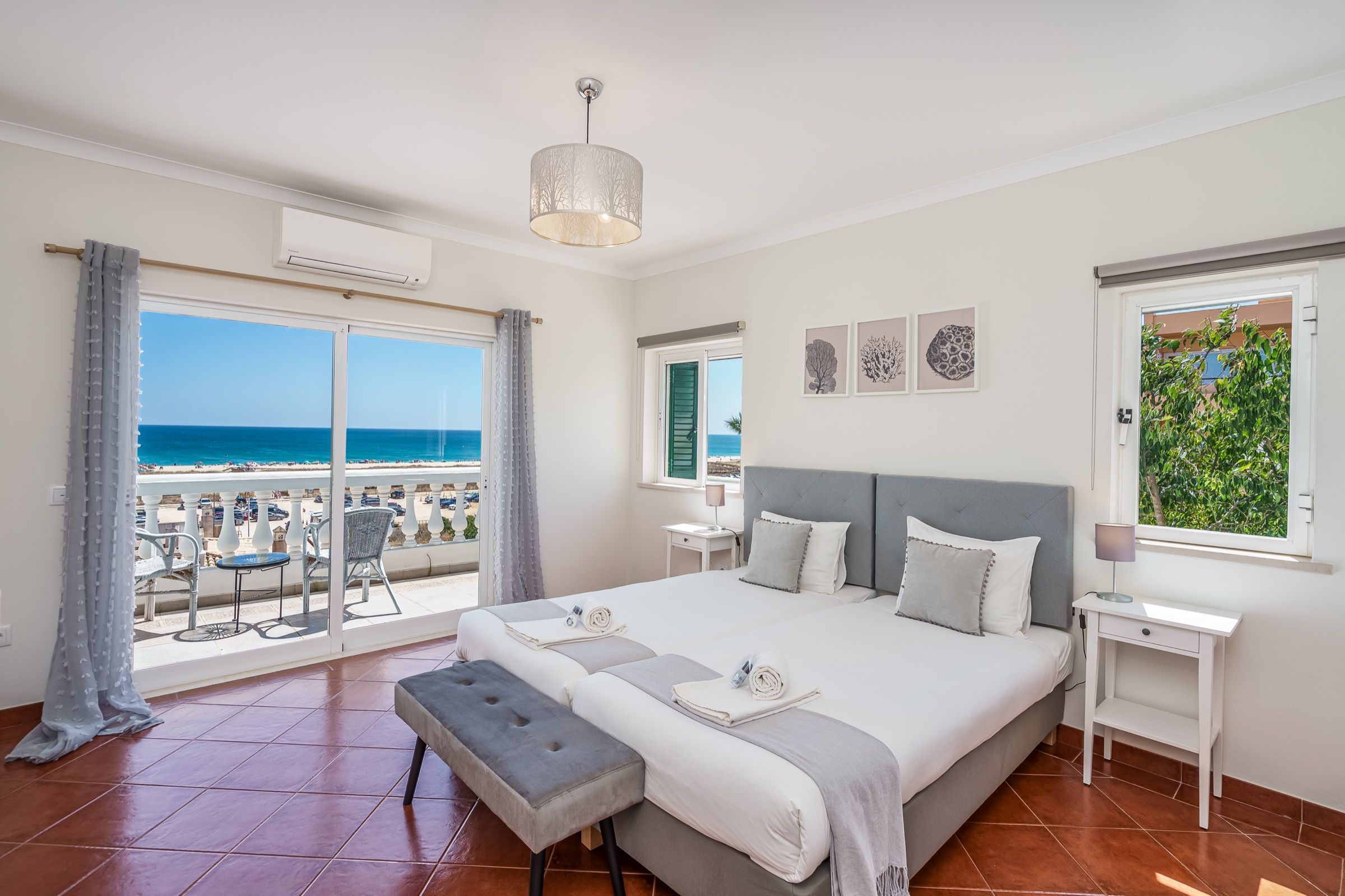 Double bedroom with a grey headboard and a glass door onto the balcony, with the sea beyond