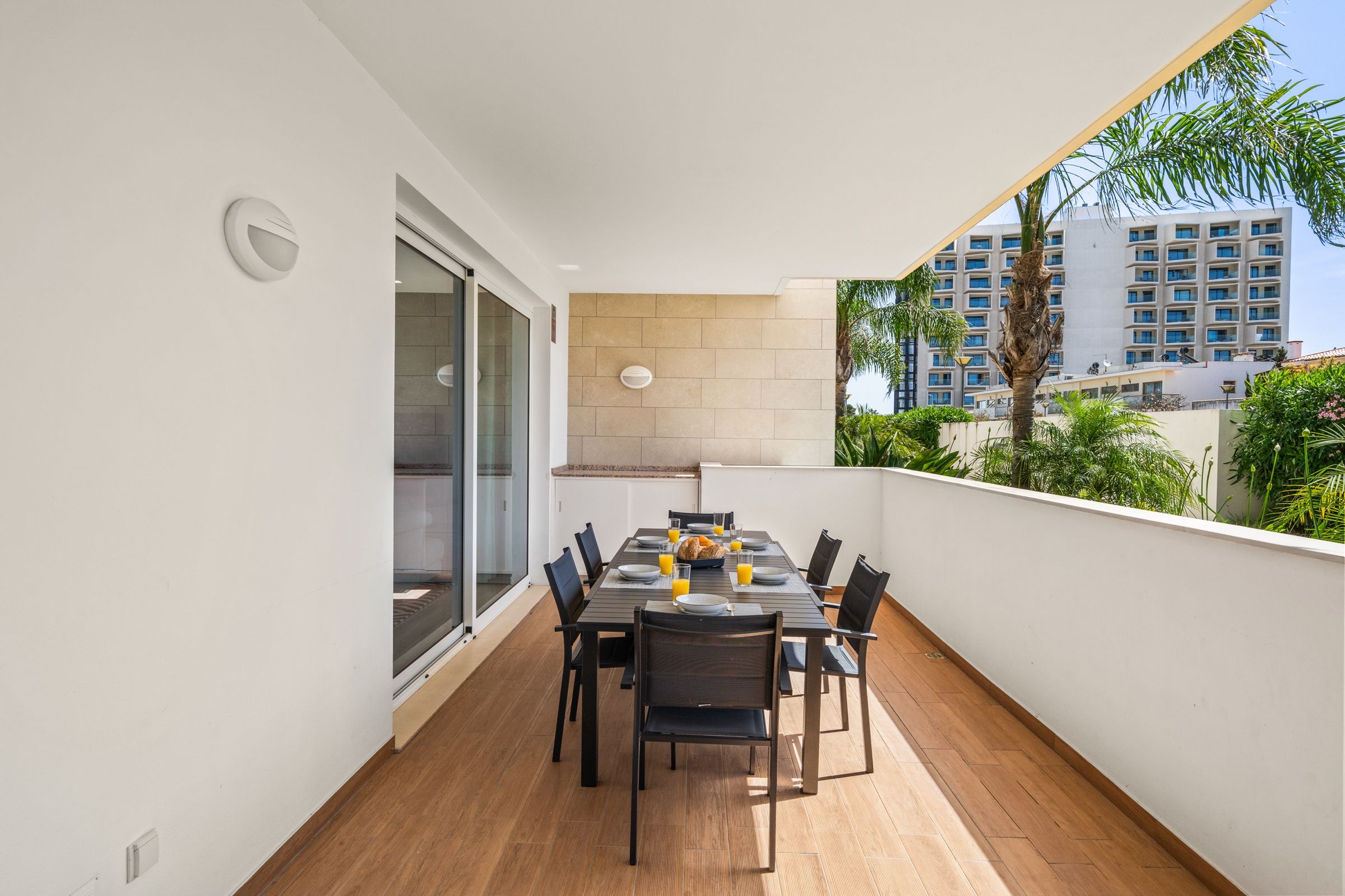 Covered balcony with a dining table laid for six and palm trees beyond