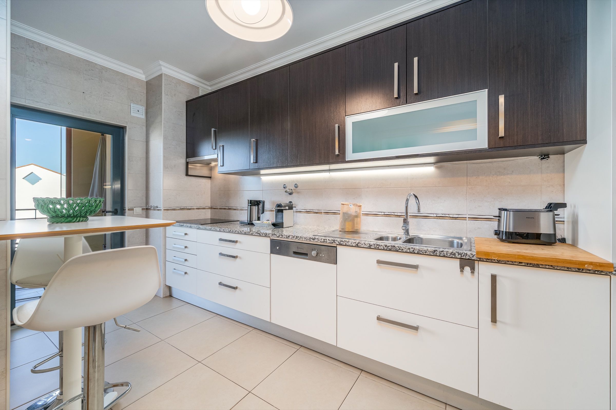 Fitted kitchen with white and dark brown cabinets and bar stools