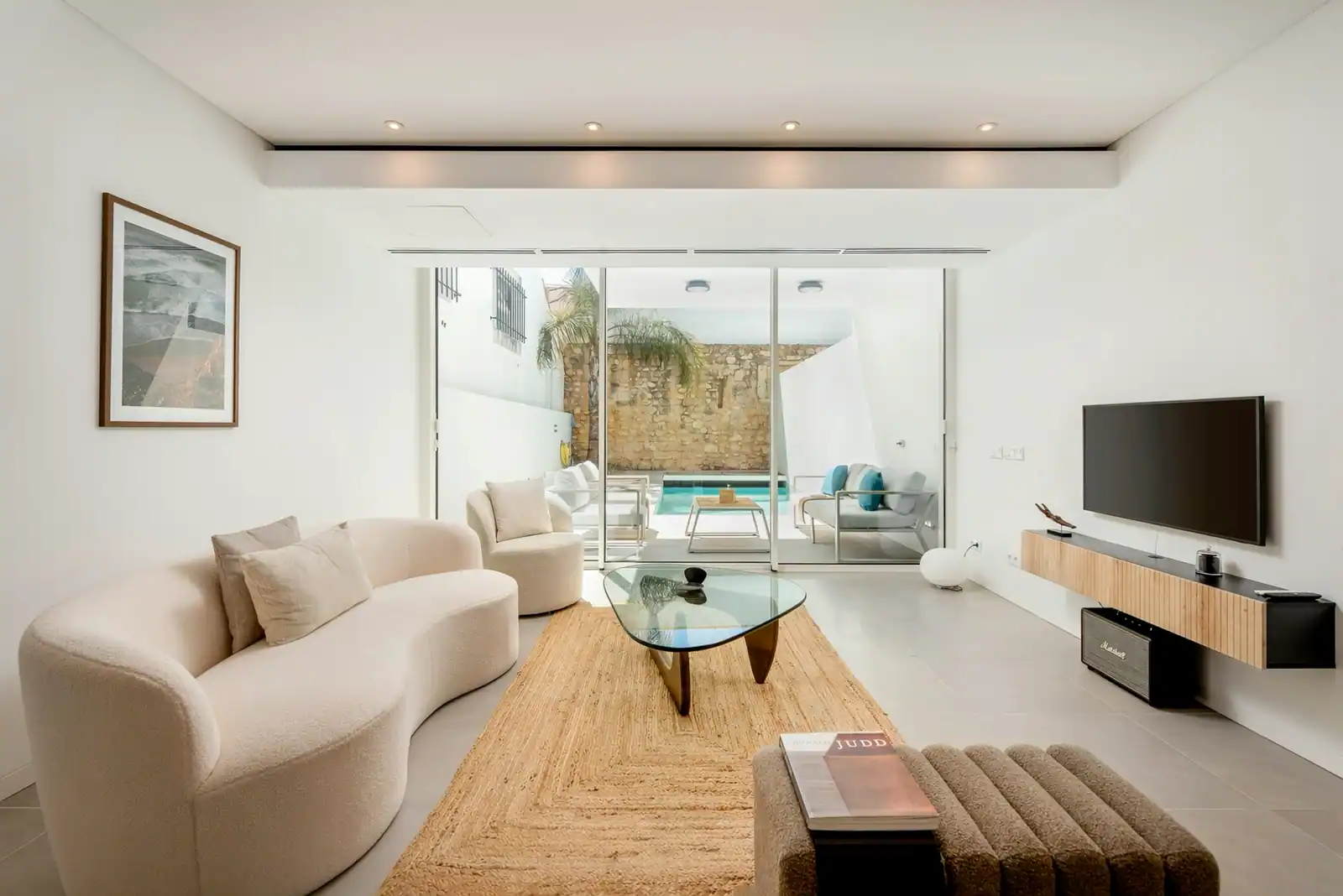 Living room of a house in the historic centre of Lagos, with pale sofas and glass doors open to a courtyard with a pool